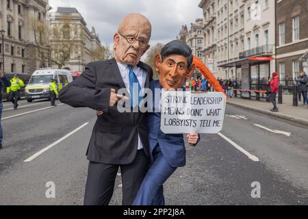 London, Großbritannien. April 2023. Zwei Aktivisten, die übergroße Karikaturmasken von politischen Persönlichkeiten tragen, protestieren auf einer Londoner Straße und halten ein satirisches Schild mit der Aufschrift „STARKE FÜHRUNG BEDEUTET ZU TUN, WAS LOBBYISTEN MIR SAGEN“. Die Demonstration kritisiert die politische Komplizenschaft mit der Lobbyarbeit von Unternehmen, die Teil einer Extinction Rebellion-Aktion in der Nähe von Regierungsgebäuden ist. Aktivisten der Extinction Rebellion veranstalten einen viertägigen Protest an verschiedenen Orten im Zentrum Londons. Die Veranstaltung heißt The Big One. Penelope Barritt/Alamy Live News Stockfoto