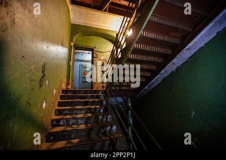 Alte, schmiedete Eisentreppe in einem schäbigen historischen Gebäude. Stockfoto
