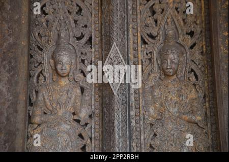 Muster von Engeln aus Holz an der Kirchentür von Wat Pa Ruak, einem verlassenen Tempel. Stockfoto