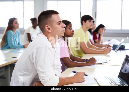 Studenten der Universität hören Vortrag während der Teilnahme an einer Klasse im Klassenzimmer. Stockfoto