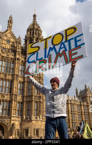 London, Großbritannien -22.04.2023, The Big One Demonstration. Mann mit einem Poster - Klimaschutzkriminalität vor dem Hintergrund des parlaments stoppen Stockfoto