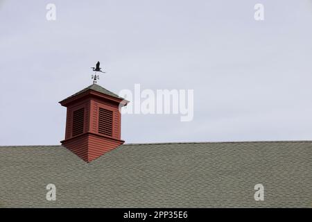 Dach der roten Scheune mit Wetterfalle oben auf dem Turm. An einem bewölkten Tag in Concord, Massachusetts, USA. Stockfoto