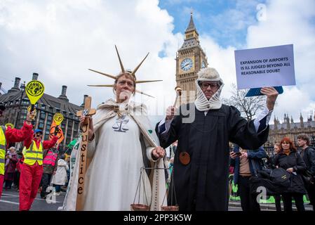London, Großbritannien. 21. April 2023. Ein Demonstrante, gekleidet wie Justitia, die Göttin der Gerechtigkeit, und der andere, gekleidet als Richter, posiert für ein Foto vor Big Ben während des demonstrationsmarsches. 180 Gruppen von Organisationen haben sich zusammengeschlossen, um vom 21. April bis zum 24. April in der Nähe des Parlaments in London, Großbritannien, tätig zu werden. Sie nennen es "The Big One". Die Organisationen beabsichtigen, die britische Regierung davon zu überzeugen, künftig keine fossilen Brennstoffe mehr zu erfinden und zu nutzen. Am ersten Tag der Aktion gab es Reden und märz. Kredit: SOPA Images Limited/Alamy Live News Stockfoto