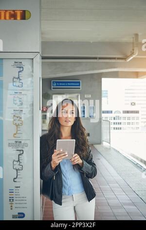 Einige digitale Verbindungen werden ermittelt. Eine junge Frau, die ein digitales Tablet am Bahnhof benutzt. Stockfoto