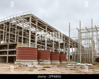 Metalllager zur Lagerung von Baumaterialien. Ein großes Lagerhaus, in dem Fässer in roter, heller Farbe stehen. Hohes offenes Lagerhaus. Stockfoto