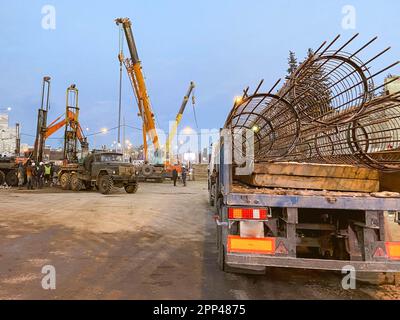 Bau einer gebrochenen Brücke an einer verkehrsreichen Straße. Die Baumaschinen auf dem Gelände errichten eine Überführung. Sperrbereich für Pkw und Fußgänger. Stockfoto