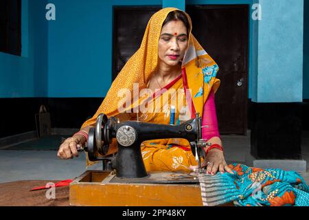 Traditionelle indische Hausfrau trägt Sari mit Nähmaschine zu Hause. Skill india-Konzept. Stockfoto