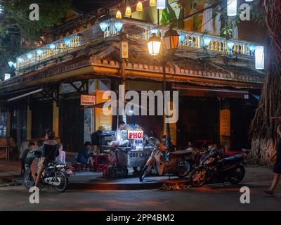 Straßenecke mit Restaurant und Street Food Küche, die Nudeln in Hoi an, Provinz Quang Nam, Vietnam am Abend verkauft. Die Altstadt von Hoi an ist ein WOR Stockfoto