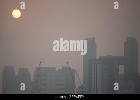 Bangkok, Thailand. 22. April 2023. Blick auf den Sonnenaufgang und die Hochhäuser inmitten von rauchigen Bedingungen aufgrund der Luftverschmutzung in Bangkok. Bangkok die thailändische Hauptstadt erlebt eine schlechte Luftqualität als Feinstaub (PM 2,5), die durch verschiedene Faktoren wie die Verbrennung von Erntefeldern und die Abgasemissionen von Fahrzeugen verursacht wird. Kredit: SOPA Images Limited/Alamy Live News Stockfoto