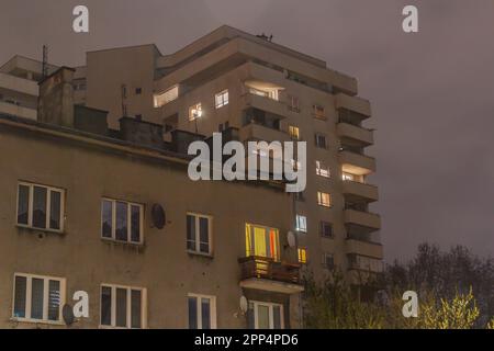 Altes Gebäude aus dem XX. Jahrhundert in Warschau mit einem neueren Gebäude im Hintergrund, das bei Nacht aufgenommen wurde Stockfoto