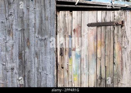 Rostiges altes Metallscharnier. Strukturierte Holztür mit rostfreiem Metallscharnier. Stockfoto