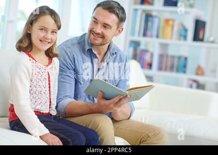 Daddy liest mir jeden Tag vor. Ein Vater, der seiner Tochter zu Hause eine Geschichte vorliest. Stockfoto