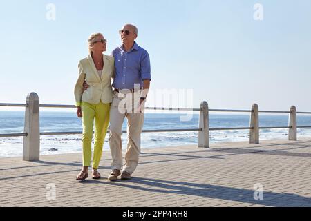 Wir genießen jeden Moment zusammen. Ein Seniorenpaar, das am Meer spaziert. Stockfoto