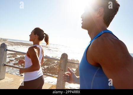 Wenn Sie es leid sind, von vorne anzufangen, hören Sie auf, aufzugeben. Ein junges Paar, das auf der Promenade joggt. Stockfoto