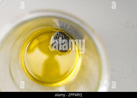 Frischer schwarzer Trüffel, der mehrere Tage lang in Olivenöl in einem Glasgefäß für hausgemachtes Trüffelöl lag, Blick von oben, Kopierraum, ausgewählter Fokus Stockfoto