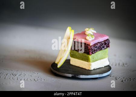 Fischvorspeise, mehrschichtiges Gericht aus rosa durchtränktem Hering, roten Zwiebeln, Gurke, Sahne-Gelatine und einem Stück Apfel, moderner Gang in einem Gourmet-Menü Stockfoto