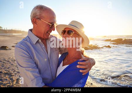 Du bist mein Sonnenschein. Ein liebevolles Seniorenpaar, das am Strand spaziert. Stockfoto