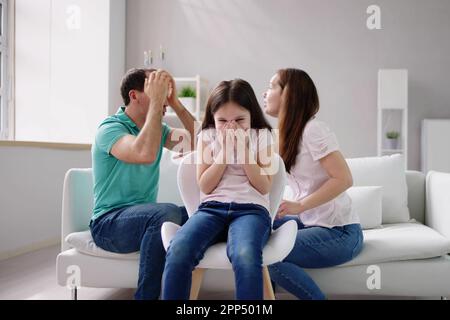 Eltern sitzen auf dem Sofa streiten Lautstark hinter Mädchen für Ihre Ohren Stockfoto