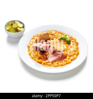 Gebackene Bohnen mit Schweinefleisch und eingelegte Gurken auf weißem Teller und gemahlen Stockfoto