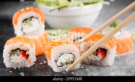 Salat, frische Sushi-Brötchen, Essstäbchen Stockfoto