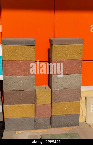 Beispiele mehrfarbiger Bausteine aus gepresstem Zement-Sand-Gemisch. Die Blöcke werden für den individuellen Aufbau und die dekorative Endbearbeitung verwendet. Stockfoto