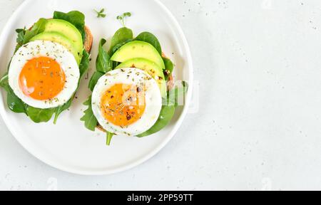 Brot mit Spiegeleiern, Avocado und Gemüse. Draufsicht, flach liegend Stockfoto