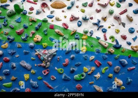 Detaildarstellung einer vertikalen Wand einer Kletterwand im Innenbereich mit Haltevorrichtungen in verschiedenen Farben, um das Klettern zu üben Stockfoto