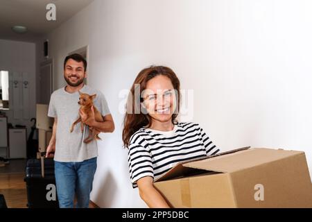 Ein junges Paar mit seinem Schoßhund zieht in ein neues Haus. Stockfoto