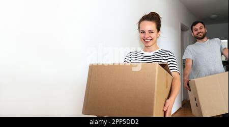 Ein junges Ehepaar trägt Pappkartons in der Hand, während es in seine neue Wohnung kommt. Bewegliches Konzept. Stockfoto