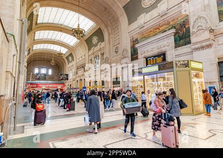 Menschen, die durch das herrliche Innere der Eingangshalle im Erdgeschoss des Mailänder Hauptbahnhofs in Mailand, Italien, spazieren Stockfoto