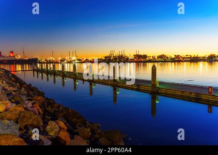 Beleuchtete Schönheit von Long Beach Harbor bei Nacht, mit dem berühmten Queen Mary Schiff und seine Reflexion im Wasser, die die atemberaubende Stadtlandschaft noch weiter untermauert Stockfoto