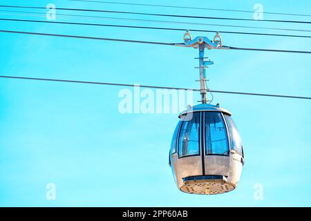 Nahaufnahme einer Skilift-Gondel und Stahlseile vor einem klaren blauen Himmelshintergrund. Stockfoto