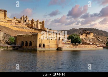 Das bernsteinfarbene Fort wird von warmem Licht der aufgehenden Sonne beleuchtet und spiegelt sich im See wider. Berühmtes Wahrzeichen von Rajasthan Stockfoto