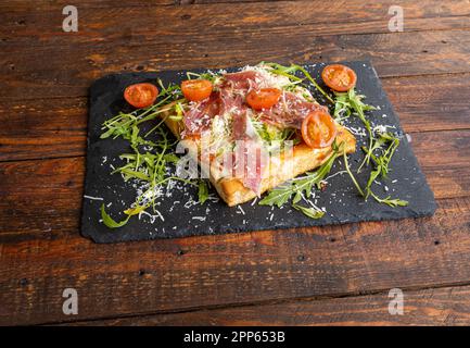 Nahaufnahme von Focaccia mit Tomaten, Rucolasalat, Jamon serrano und Parmesan Stockfoto