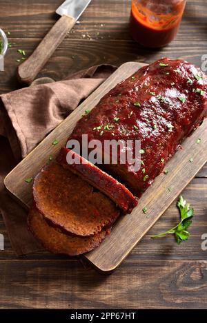 Hackbraten mit Glasur auf dem Schneidebrett auf Holzhintergrund. Stockfoto