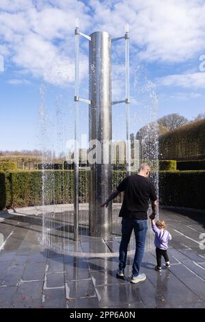 Eine Familie mit Kindern, die im Frühlingssonnenbereich im Alnwick Garden, Alnwick northumberland UK spielen Stockfoto