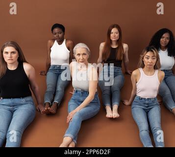 Sechs verschiedene Frauen auf braunem Hintergrund. Eine Gruppe von sechs Frauen mit unterschiedlichen Körpertypen und Hauttönen schaut auf die Kamera. - Weibchen mit unterschiedlichem A. Stockfoto