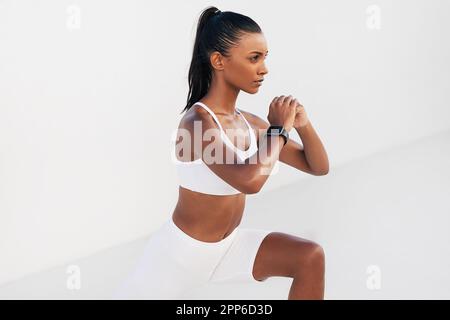 Gekürzt von einer jungen Frau in weißer Fitnesskleidung, die Kardio-Übungen macht. Slim Woman wärmt sich auf. Stockfoto