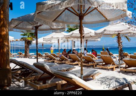 Ein Sandstrand mit mehreren Liegestühlen und Sonnenschirmen zum Entspannen. Stockfoto