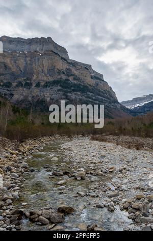 Ein Bergfluss fließt durch ein Tal zwischen großen felsigen Bergen, dem Fluss Arazas, dem Nationalpark Ordesa y Monte Perdido, Huesca, den Pyrenäen Aragonese, Stockfoto