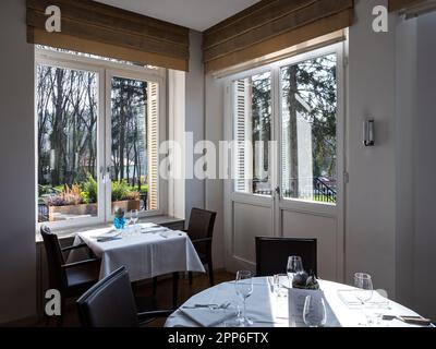 Gemütliches Interieur des Restaurants. Raum gefüllt mit der Morgensonne. Tische sind gedeckt und bereit für den Empfang der Gäste. Wärme und Tragekomfort. Stockfoto