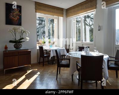 Gemütliches Interieur des Restaurants. Raum gefüllt mit der Morgensonne. Tische sind gedeckt und bereit für den Empfang der Gäste. Wärme und Tragekomfort. Stockfoto