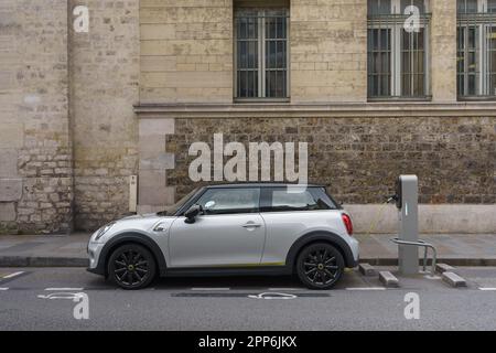 Weißes Elektroauto an einer Ladestation auf der Straße. Paris, Frankreich. Stockfoto