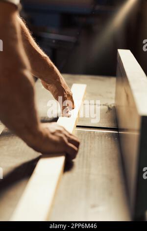 Die starke und muskulöse Hand und der Unterarm eines Zimmermanns, der ein Metallwerkzeug hält und es verwendet, um beim Bau eines Möbelstücks zu helfen, das es sein wird Stockfoto