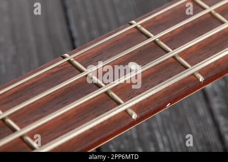 Bass-Gitarrenfretboard mit Holzhintergrund Stockfoto