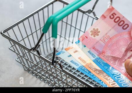 Konzept, chilenische Inflation, leerer Einkaufswagen und chilenische Pesos-Akte, Nahaufnahme Stockfoto