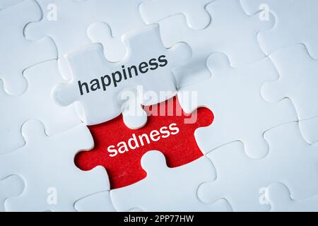 Glück und Traurigkeit, Emotionen, Freude und Enttäuschung, Moods ändern sich, positiv und negativ, White Happy Puzzle enthüllt roten Hintergrund mit Traurigkeit Stockfoto