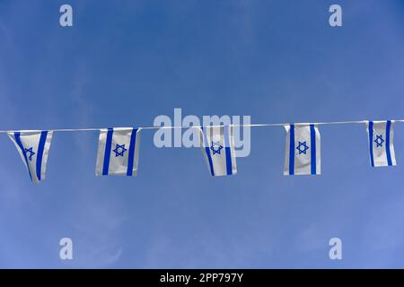 Am Unabhängigkeitstag Israels flattert die israelische Flagge vor dem Hintergrund des blauen Himmels mit weißen Wolken. Stockfoto