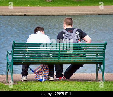 two teenagers on a bench near a pond Stock Photo