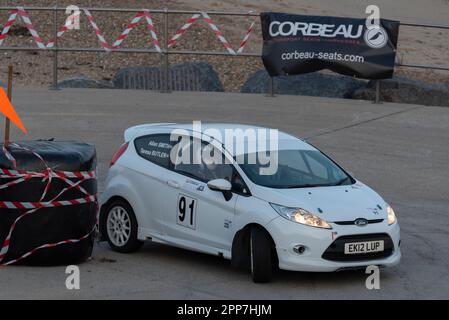 Seafront, Clacton on Sea, Essex, Großbritannien. 22. April 2023. Die Corbeau Seats Rally, die vom Chelmsford Motor Club organisiert wird, findet rund um Tendring und Clacton, Essex, statt und beginnt mit den Etappen 1 und 2 auf den Straßen unterhalb der Clacton on Sea Parade auf den Klippen. Autos verschiedener Gruppen, darunter Klassiker, nahmen an der Bühne Teil, die um 18:00 Uhr begann und um 21:00 im Dunkeln enden sollte. Ein Auto rollte auf die Bühne, wodurch es früh angehalten wurde. Ford Fiesta EK12LUP, gefahren von Allan Smith, Mitfahrerin Teresa Butler Stockfoto